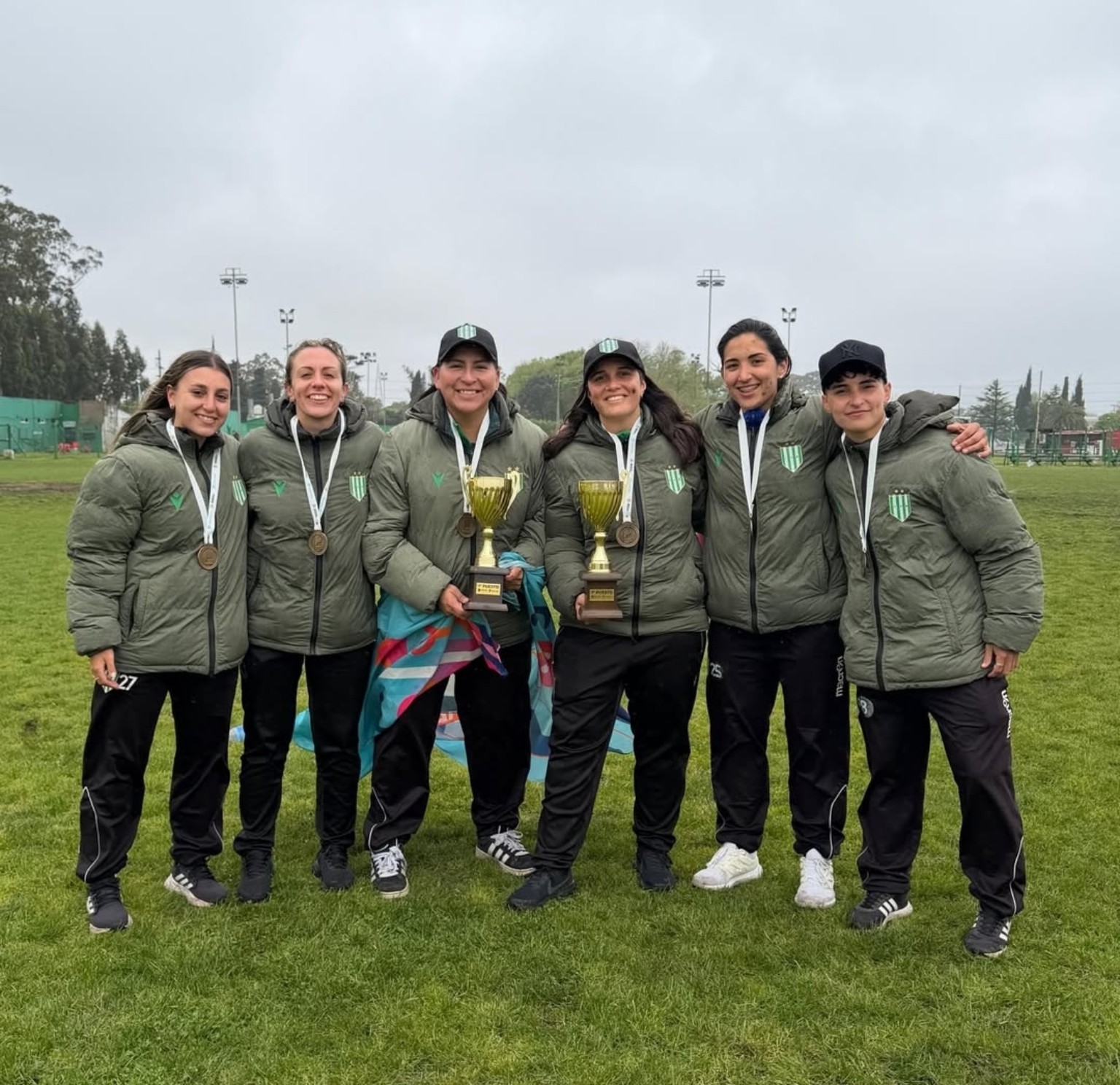 El cuerpo técnico de Banfield junto a las dos copas y las medallas de la competencia provincial.